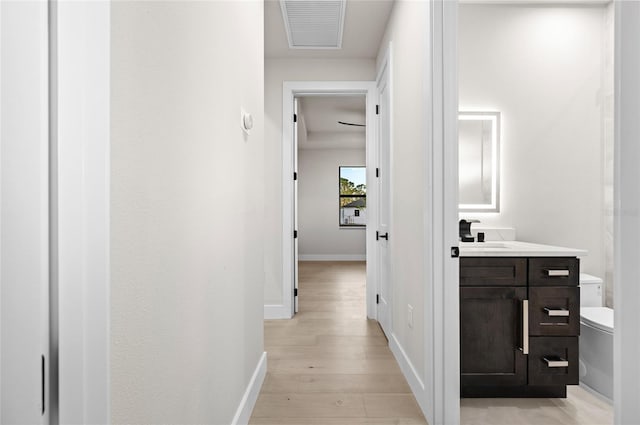 hallway with sink and light hardwood / wood-style flooring