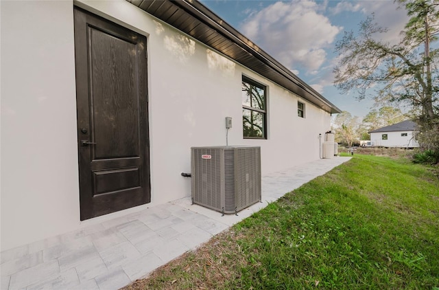 view of side of property with central AC and a lawn