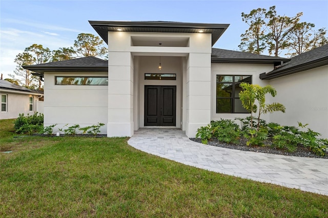 view of exterior entry featuring a lawn