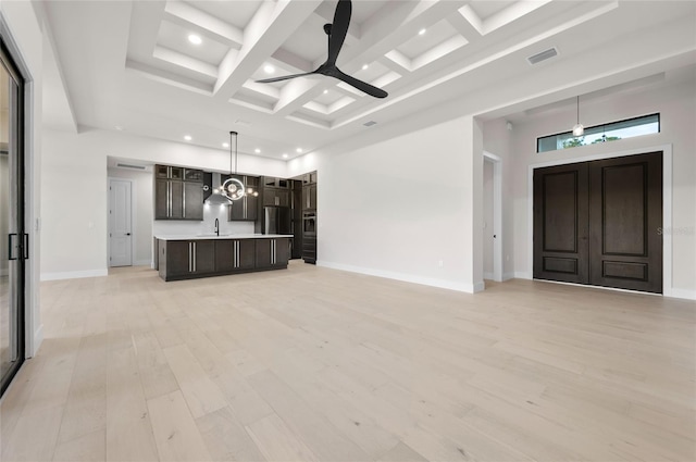 unfurnished living room featuring sink, light hardwood / wood-style flooring, ceiling fan, a high ceiling, and coffered ceiling