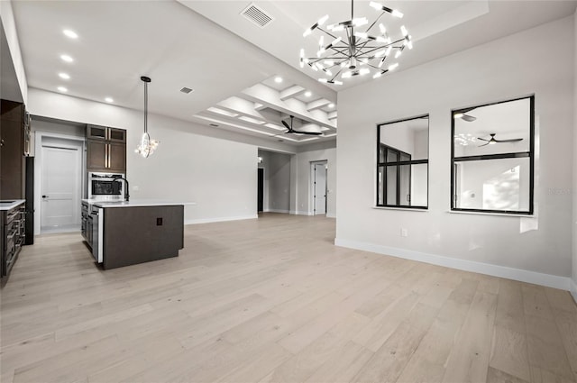 interior space featuring a center island with sink, ceiling fan with notable chandelier, light hardwood / wood-style floors, and decorative light fixtures