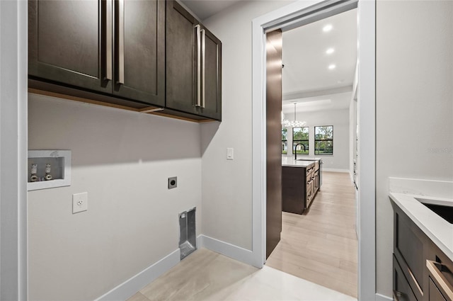 laundry area with sink, electric dryer hookup, cabinets, washer hookup, and light wood-type flooring