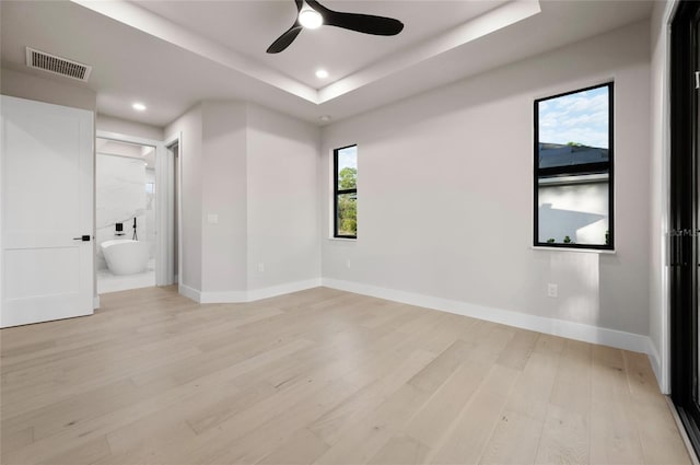 spare room with a raised ceiling, ceiling fan, and light wood-type flooring