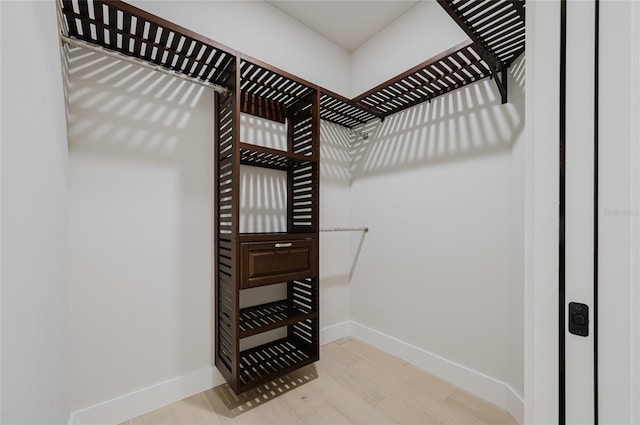 walk in closet with light hardwood / wood-style floors