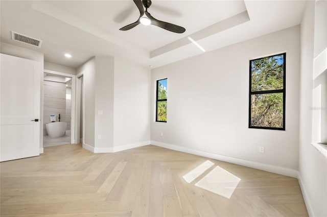 unfurnished bedroom with connected bathroom, a tray ceiling, and ceiling fan