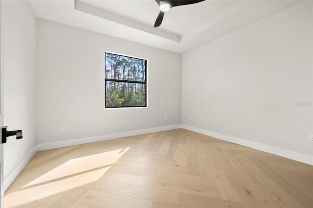 unfurnished room with ceiling fan, a tray ceiling, and light parquet flooring