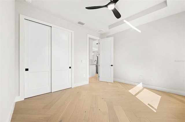 unfurnished bedroom with light parquet flooring, a closet, and ceiling fan