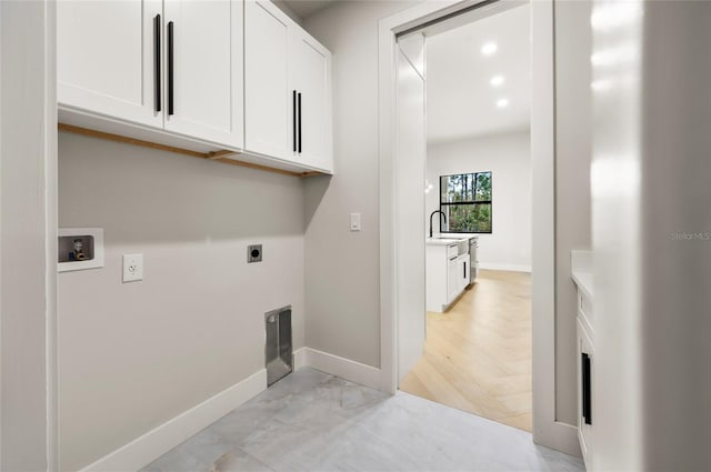 clothes washing area with cabinets, sink, hookup for an electric dryer, and hookup for a washing machine