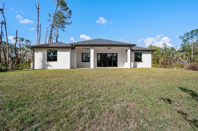 rear view of property featuring a yard and ceiling fan