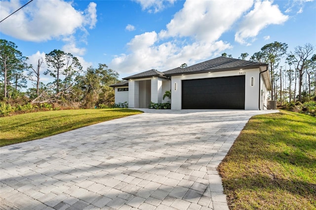 view of front of home featuring a garage, a front lawn, and central air condition unit