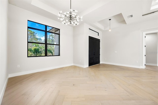 unfurnished room featuring light parquet flooring, a barn door, a chandelier, and a tray ceiling