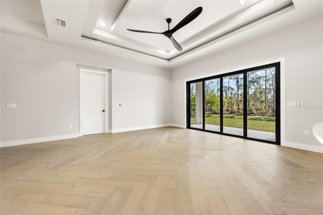 empty room featuring ceiling fan, light parquet flooring, a raised ceiling, and a towering ceiling