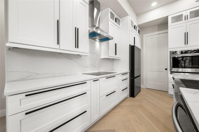 kitchen featuring white cabinetry, light parquet floors, black appliances, light stone countertops, and wall chimney exhaust hood