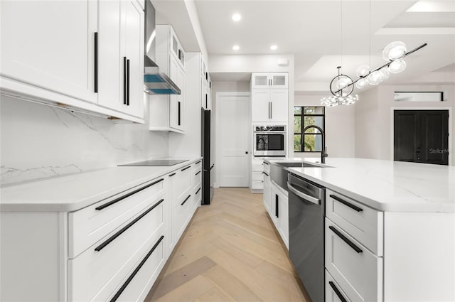 kitchen featuring sink, white cabinetry, black appliances, pendant lighting, and wall chimney range hood