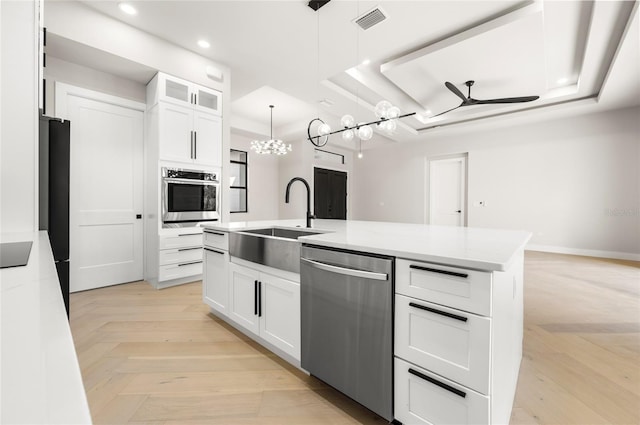 kitchen featuring a raised ceiling, white cabinetry, appliances with stainless steel finishes, and pendant lighting