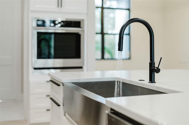 room details featuring white cabinetry, sink, and oven