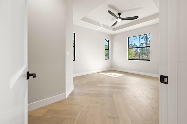 spare room featuring ceiling fan, a raised ceiling, and light parquet floors