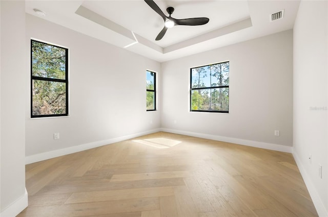 spare room featuring light parquet floors, a raised ceiling, and ceiling fan