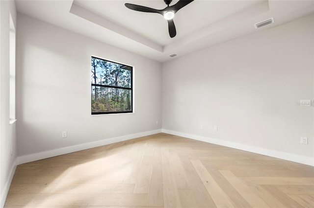 spare room with parquet flooring, a raised ceiling, and ceiling fan