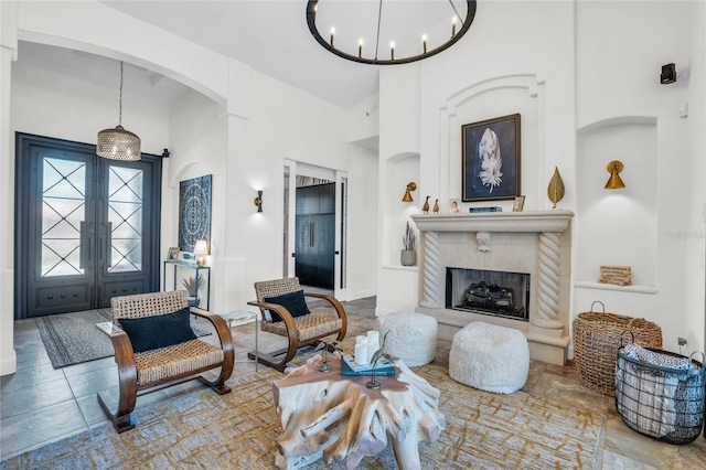 living room featuring a chandelier, french doors, a towering ceiling, and a premium fireplace