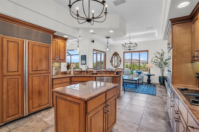 kitchen with a center island, sink, a raised ceiling, decorative light fixtures, and black electric cooktop