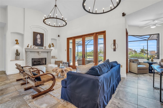 living room with a high ceiling, ceiling fan with notable chandelier, and french doors