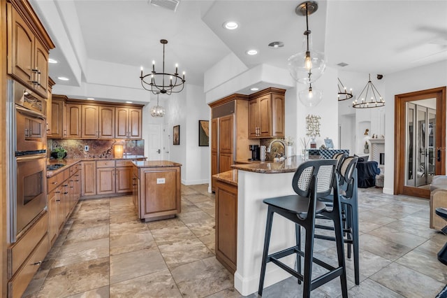 kitchen with a brick fireplace, tasteful backsplash, decorative light fixtures, a breakfast bar, and a kitchen island