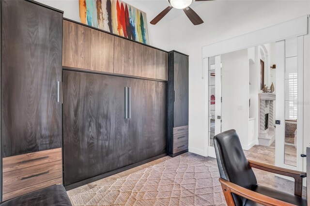 office featuring a stone fireplace and ceiling fan