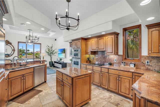 kitchen with sink, stainless steel appliances, a raised ceiling, a chandelier, and decorative light fixtures