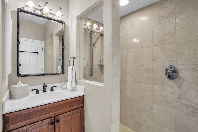 bathroom featuring a tile shower and vanity