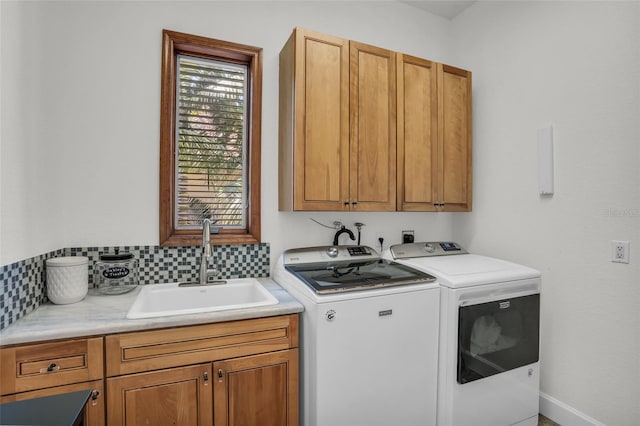 clothes washing area with washer and dryer, cabinets, and sink