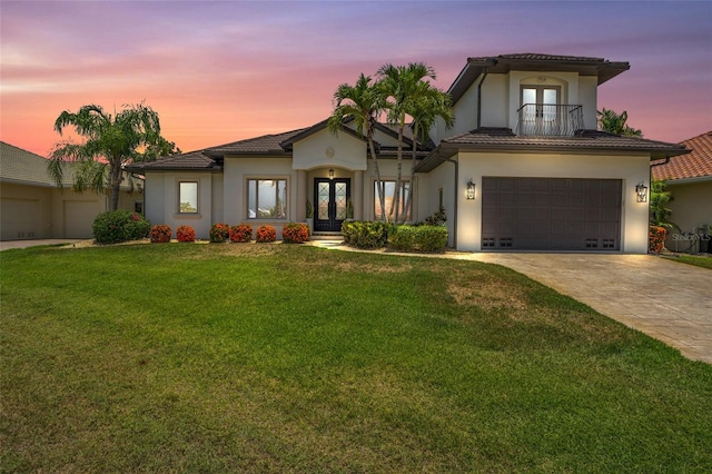 view of front of home with french doors, a yard, a balcony, and a garage