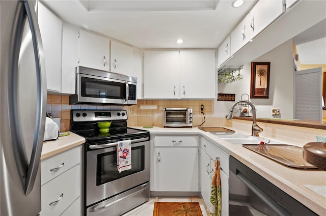 kitchen featuring white cabinets, appliances with stainless steel finishes, decorative backsplash, and sink