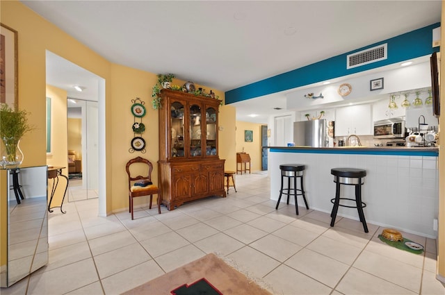 kitchen with light tile patterned floors, white cabinetry, kitchen peninsula, and appliances with stainless steel finishes