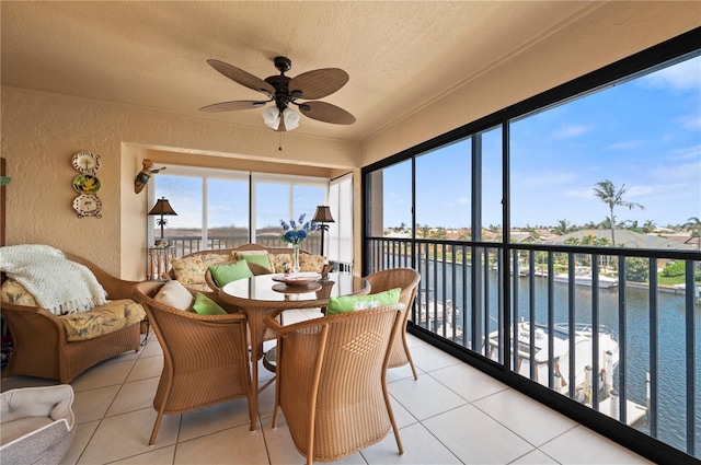 sunroom with ceiling fan and a water view