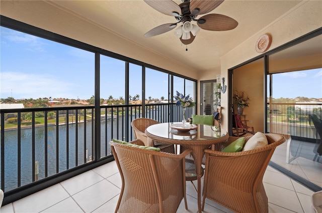 sunroom / solarium with plenty of natural light, ceiling fan, and a water view