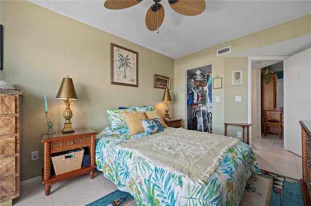 tiled bedroom featuring a walk in closet, a closet, and ceiling fan