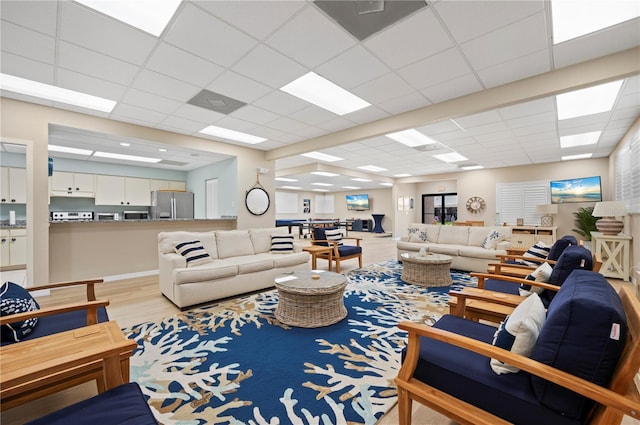 living room with a drop ceiling and light wood-type flooring