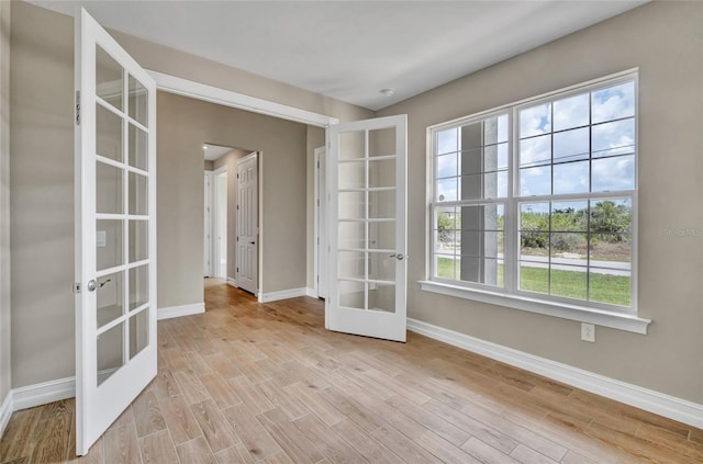 spare room featuring french doors and light wood-type flooring