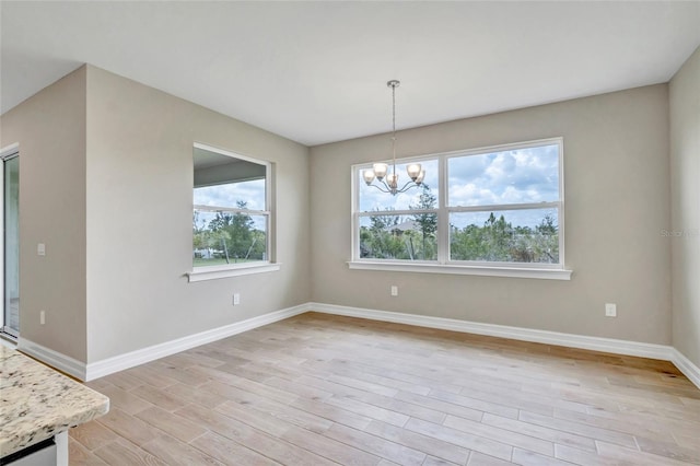 unfurnished dining area featuring a notable chandelier and light wood-type flooring