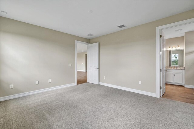 unfurnished bedroom featuring light carpet and ensuite bath