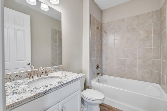 full bathroom featuring tiled shower / bath combo, wood-type flooring, toilet, and vanity