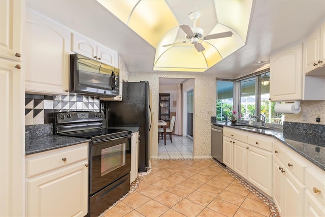 kitchen with dark stone counters, a ceiling fan, a raised ceiling, black appliances, and a sink