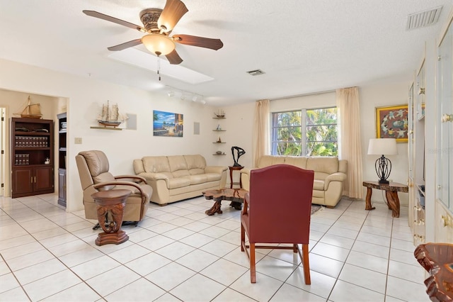 living area with light tile patterned floors, ceiling fan, visible vents, and a textured ceiling