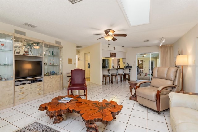 living area featuring a ceiling fan, visible vents, a textured ceiling, and light tile patterned floors