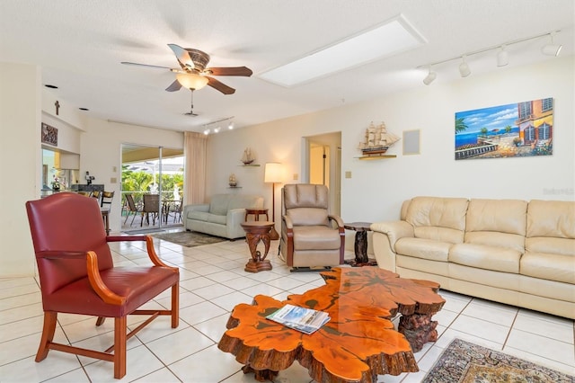 living room with a skylight, ceiling fan, a textured ceiling, and light tile patterned floors