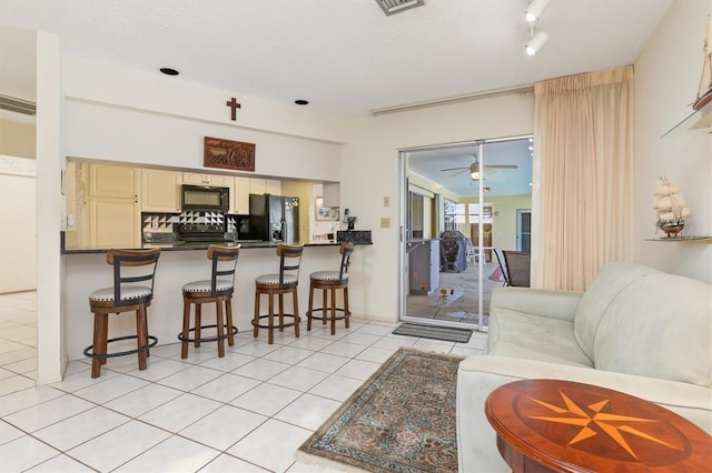 living area with ceiling fan, a textured ceiling, and light tile patterned floors