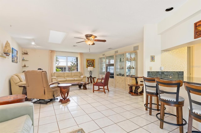 living area featuring light tile patterned floors, visible vents, a skylight, and a ceiling fan