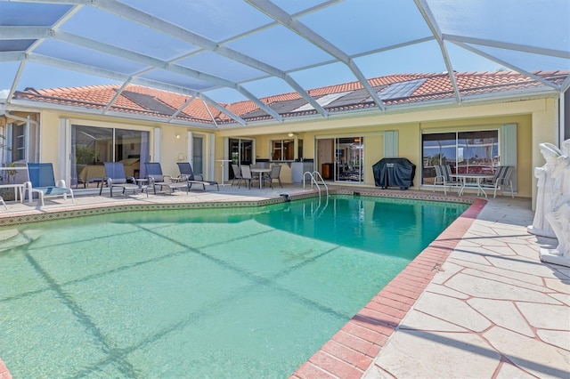 pool featuring glass enclosure, a grill, and a patio area