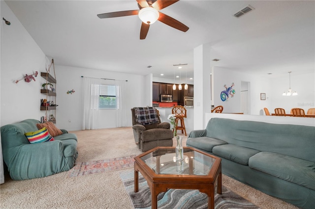 living room featuring carpet floors and ceiling fan with notable chandelier